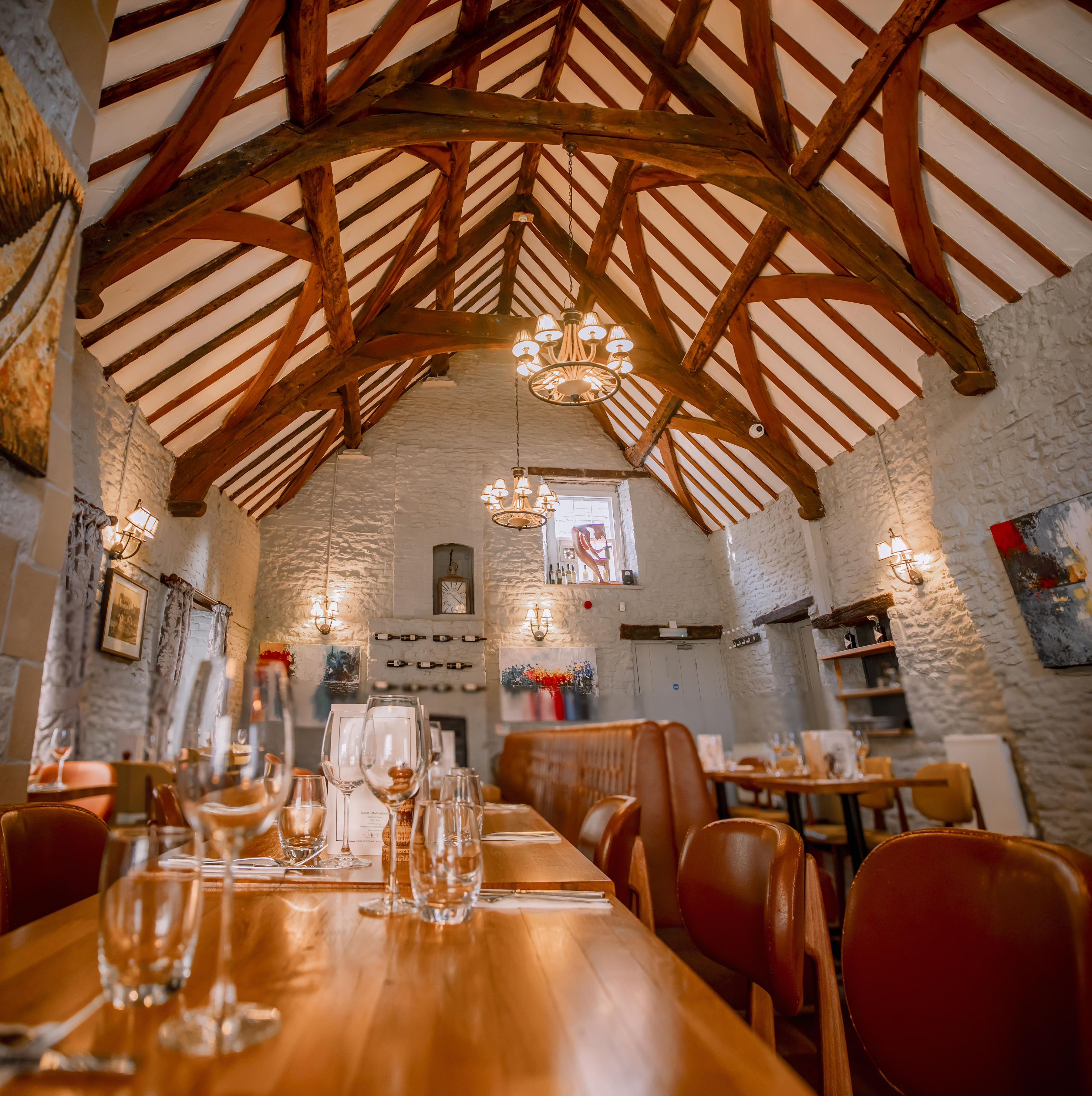 The welcoming Jackdaws dining room with exposed wooden beams and warmly set tables
